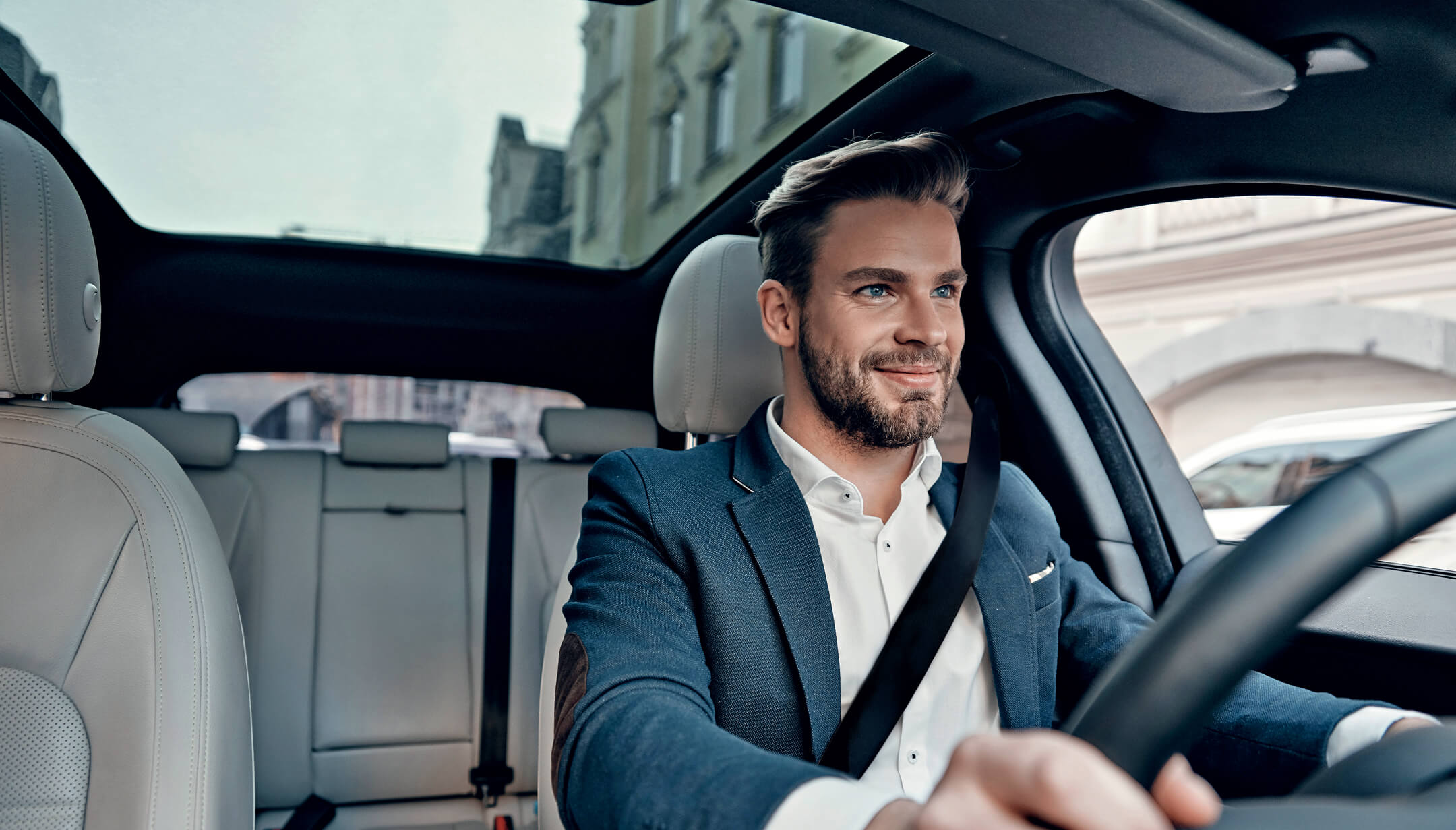 Un conducteur souriant vu de face à l'intérieur d'une voiture