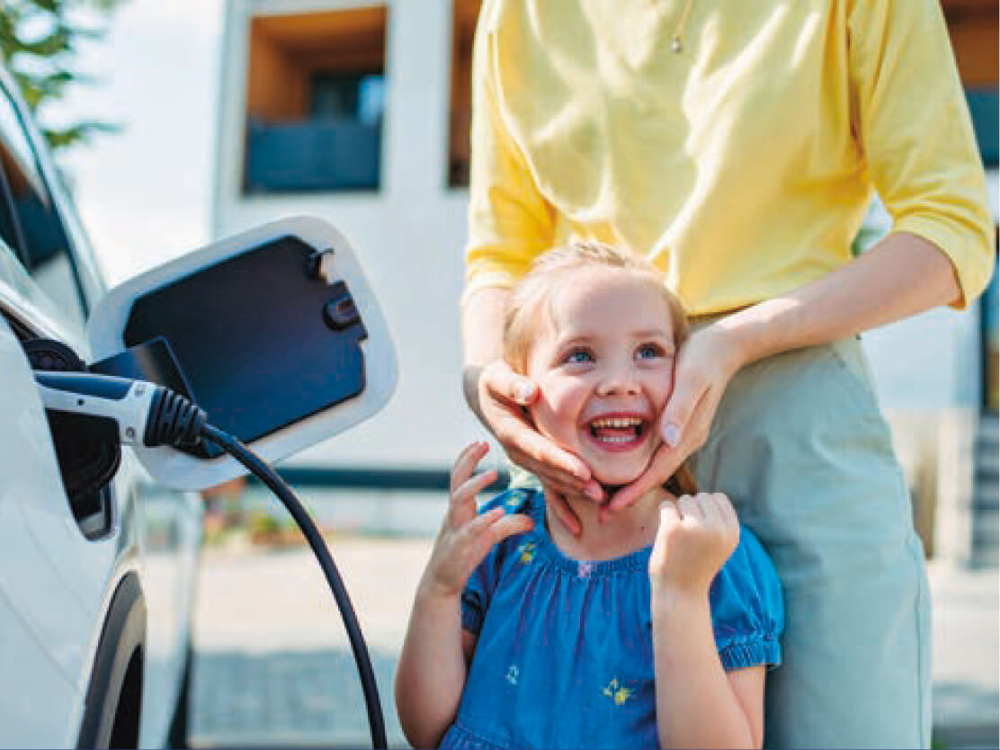 Une femme qui caresse le visage d'une fille à côté d'un véhicule électrique en charge